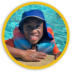 Young boy in water at edge of pool